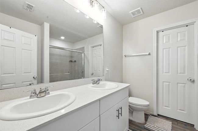 Bathroom with double vanity, a stall shower, and wood finished floors | Image 27