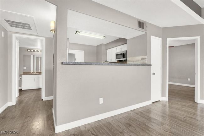 Kitchen featuring baseboards, appliances with stainless steel finishes, wood finished floors, and visible vents | Image 9