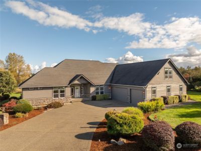 This aerial shot showcases the grandeur of the extra-wide driveway that leads directly to the front steps, making arrivals a breeze. The L-shaped design of the home adds a touch of sophistication, creating an inviting courtyard-style space that welcomes you right at the front! Imagine your holiday displays shining bright on this charming entry! With paved access leading right to the door, it’s an inviting introduction to your home that says, ‘Come on in!’—and who could resist a welcome like that? | Image 1