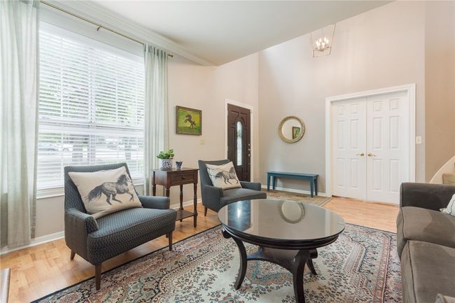 Living area with healthy amount of natural light, wood finished floors, and a chandelier | Image 4