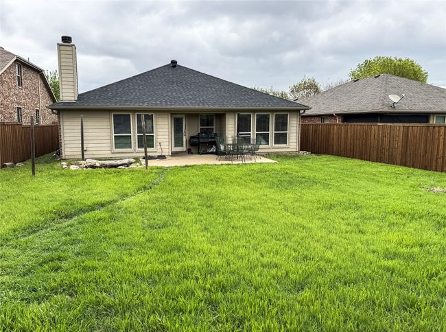 Rear view of house featuring roof with shingles, a chimney, a patio area, a fenced backyard, and a yard | Image 22