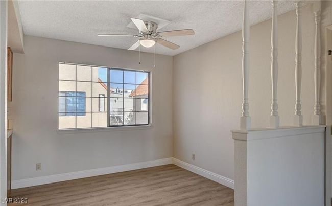 Spare room featuring wood finished floors, a textured ceiling, baseboards, and a ceiling fan | Image 6