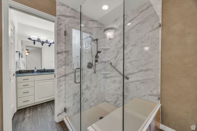 Full bathroom featuring lofted ceiling, vanity, a marble finish shower, and wood finished floors | Image 19
