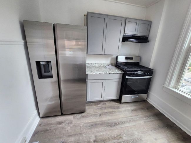 Kitchen featuring appliances with stainless steel finishes, gray cabinetry, under cabinet range hood, and light wood finished floors | Image 5