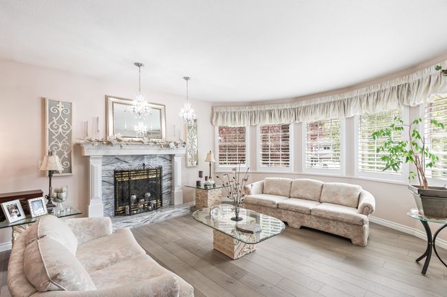 Living room featuring a high end fireplace, baseboards, a chandelier, and wood finished floors | Image 8