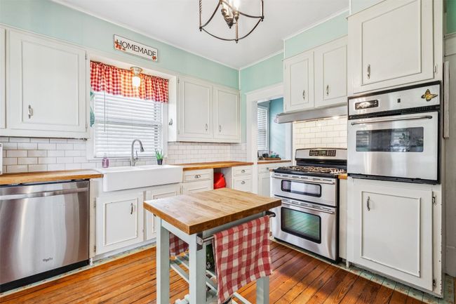 Kitchen featuring wood counters, stainless steel appliances, healthy amount of natural light, a chandelier, and ornamental molding | Image 15