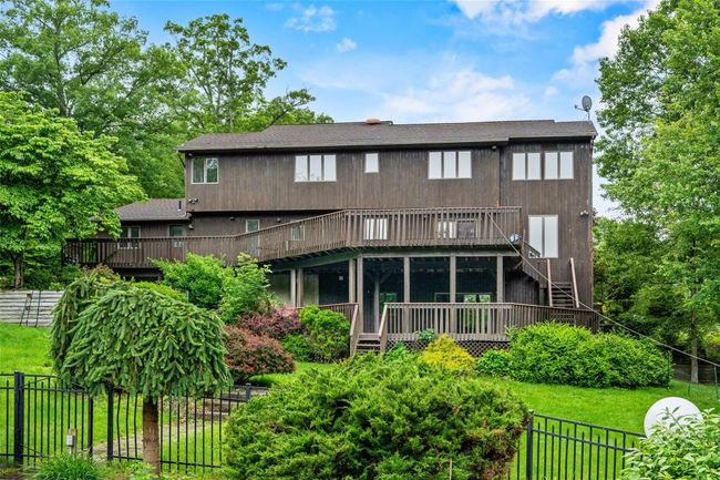 Rear view of house with a deck, stairway, and roof with shingles | Image 42