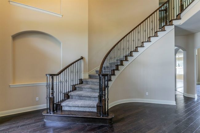 Staircase with arched walkways, wood finished floors, a towering ceiling, and baseboards | Image 7
