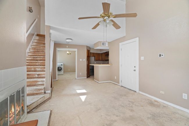 Unfurnished living room featuring washer / clothes dryer, a ceiling fan, and stairs | Image 5