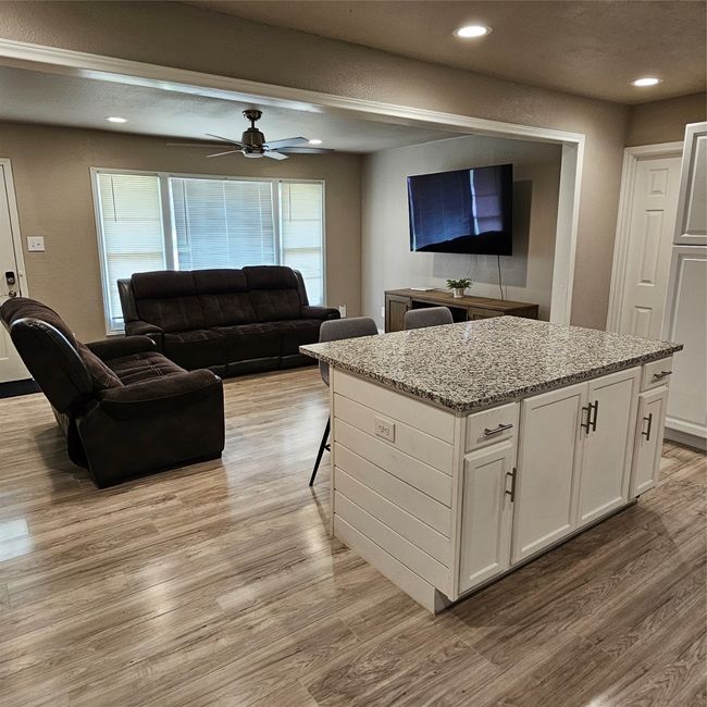Step inside to an open floorplan connecting the living, dining, and kitchen areas featuring light wood-type flooring, ceiling fan, and recessed lighting. | Image 6