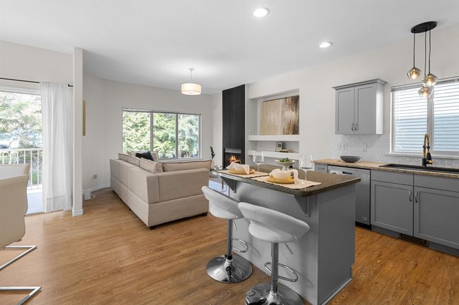 Kitchen featuring a sink, gray cabinetry, stainless steel dishwasher, light wood finished floors, and a kitchen island | Image 17