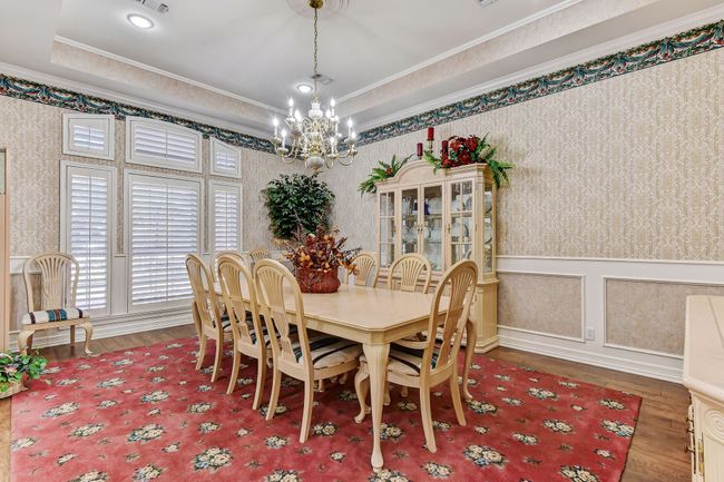 Dining area featuring wallpapered walls, wood finished floors, ornamental molding, and a notable chandelier | Image 7