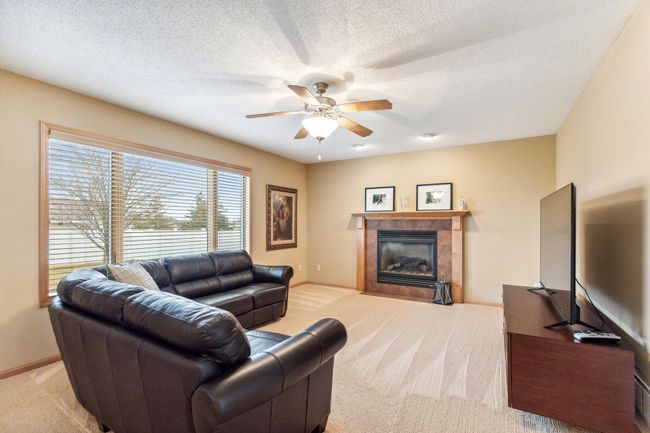 A large family room with a gas fireplace and plush carpet. The large windows keep it bright and cozy. | Image 7
