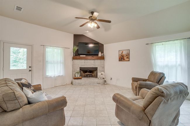 Living room featuring lofted ceiling, ceiling fan, light tile patterned floors, and a brick fireplace | Image 17