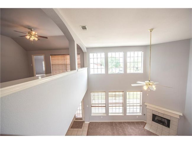 Unfurnished living room with a ceiling fan, a tiled fireplace, and baseboards | Image 8