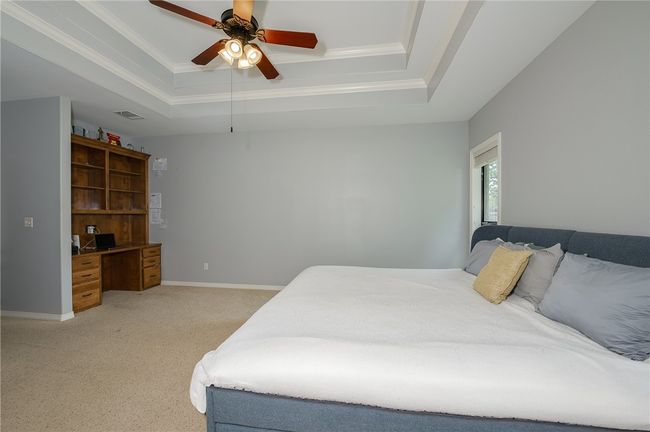 Bedroom featuring crown molding, light colored carpet, visible vents, and a raised ceiling | Image 16