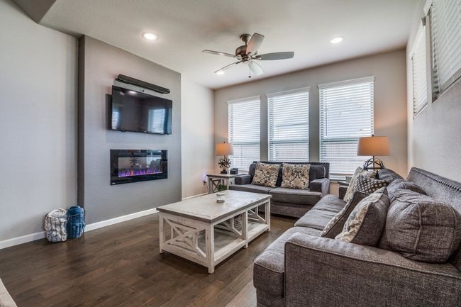 Living room featuring a glass fireplace, a ceiling fan and a great view of the back yard. | Image 4