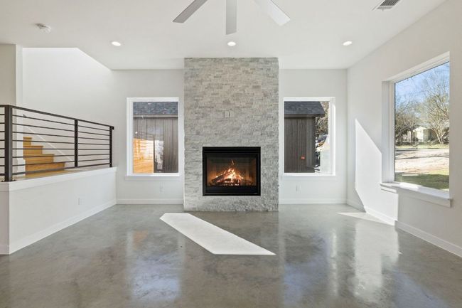 Living room with finished concrete flooring, a fireplace, and baseboards | Image 5