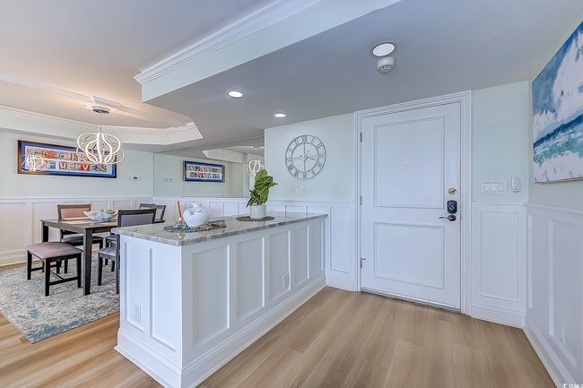 Kitchen featuring light wood-type flooring, a chandelier, kitchen peninsula, light stone countertops, and hanging light fixtures | Image 7