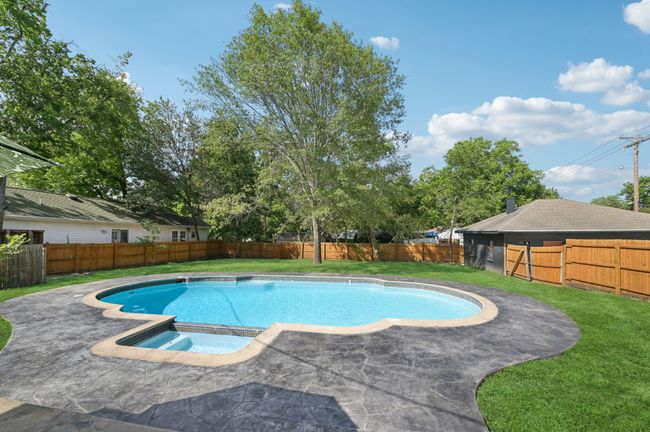 View of swimming pool featuring a patio area and a pool with connected hot tub | Image 38