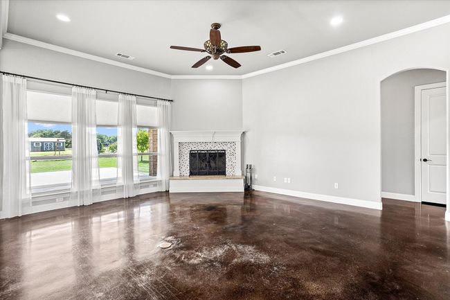 Unfurnished living room with arched walkways, a ceiling fan, a tiled fireplace, recessed lighting, and baseboards | Image 8