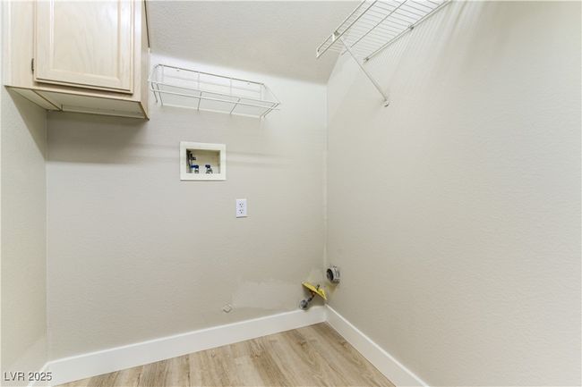 Washroom with cabinet space, washer hookup, light wood-type flooring, baseboards, and hookup for a gas dryer | Image 18
