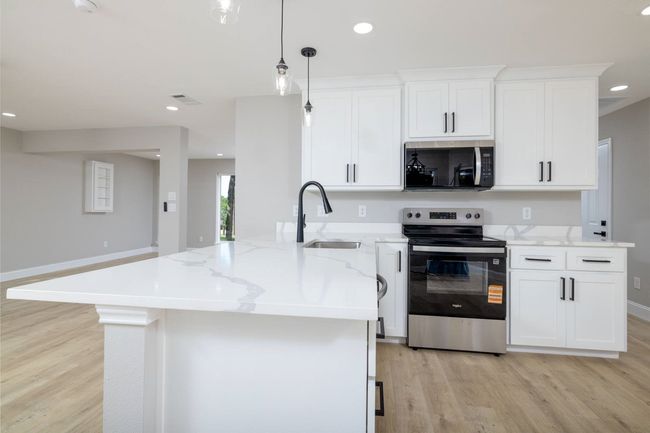 Kitchen with appliances with stainless steel finishes, light wood-style floors, white cabinets, light stone countertops, and recessed lighting | Image 16