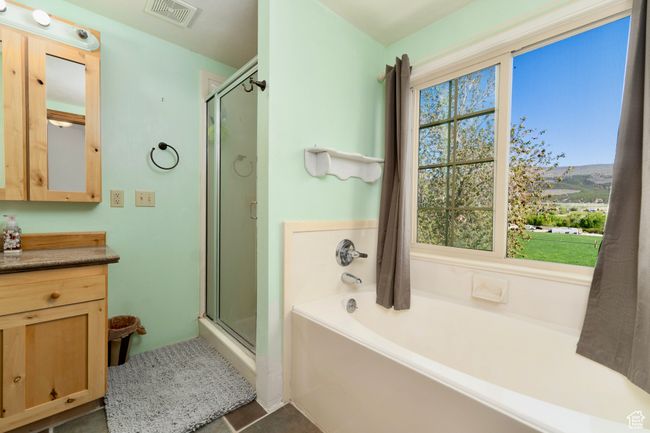 Bathroom featuring a stall shower, vanity, and a garden tub | Image 23