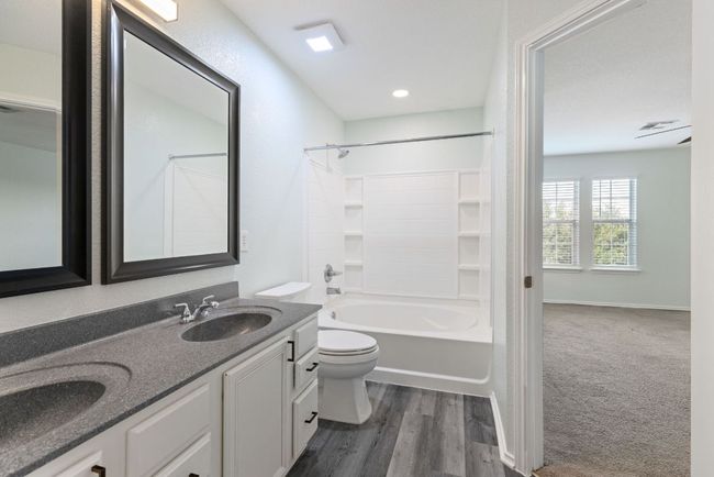 Full bath featuring toilet, double vanity, shower combination, Grey wood-style vinyl floors, and recessed lighting | Image 20