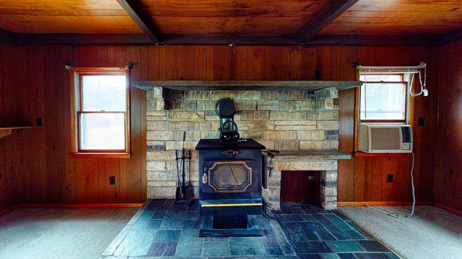 Details featuring beam ceiling, a wood stove, wood walls, carpet, and wood ceiling | Image 4