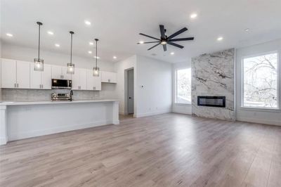 Kitchen with appliances with stainless steel finishes, white cabinets, a fireplace, pendant lighting, and ceiling fan | Image 3