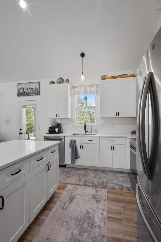 Kitchen featuring stainless steel appliances, light wood-style flooring, white cabinetry, and light countertops | Image 15