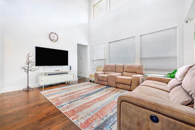 Living room with wood finished floors, a high ceiling, and healthy amount of natural light | Image 7