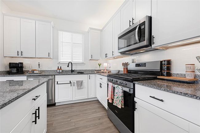 Modern kitchen with granite countertops, stainless steel appliances, ample cabinetry, and oversized island. | Image 7