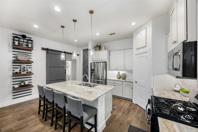A thoughtful layout includes plenty of counter space, open shelving, and a walk-in pantry to keep everything organized while maintaining the home’s modern aesthetic. | Image 10
