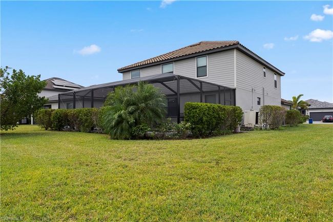 Rear view of house featuring a lawn, a tile roof, and a lanai | Image 39