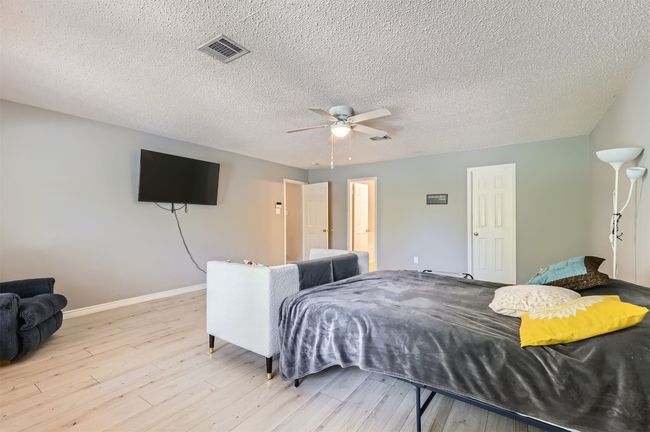 Bedroom featuring light wood-type flooring, baseboards, a textured ceiling, and ceiling fan | Image 15