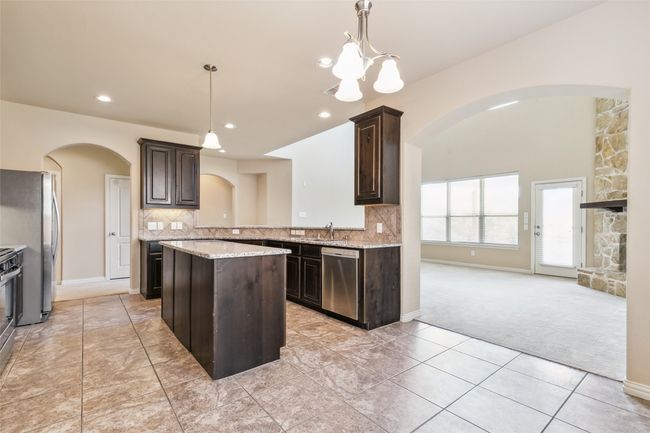 Kitchen with stainless steel appliances, arched walkways, light carpet, dark brown cabinets, and recessed lighting | Image 17