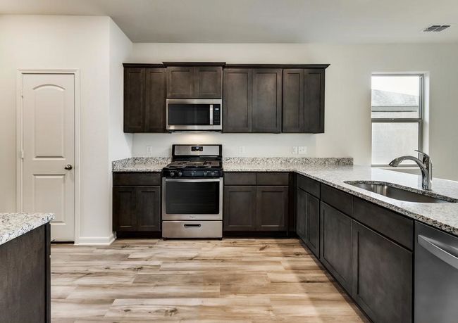 Kitchen featuring visible vents, a sink, dark brown cabinetry, appliances with stainless steel finishes, and light wood finished floors | Image 5