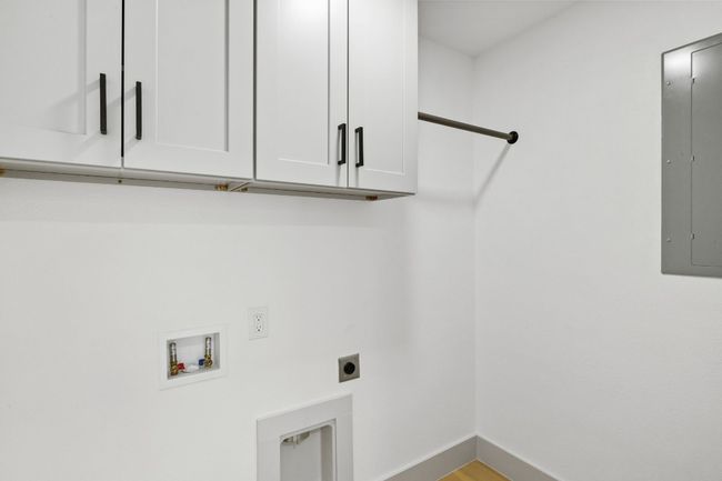 The laundry room is located inside the home next to the guest bathroom. Notice the storage cabinets above where the washer and dryer will be placed. | Image 16