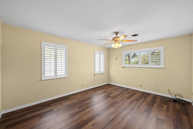 Bedroom featuring LVP finished floors, a ceiling fan, and baseboards | Image 19