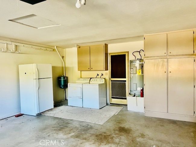 Garage has storage closets, work bench, and laundry area | Image 44