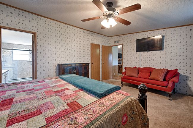 Carpeted bedroom with ornamental molding, a textured ceiling, wallpapered walls, and ceiling fan | Image 12