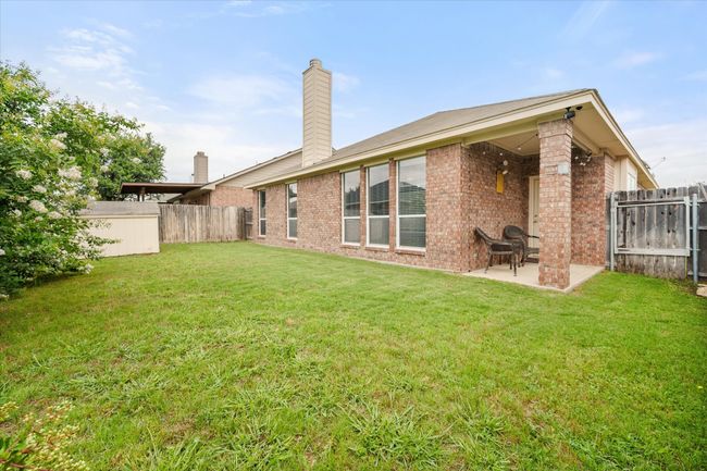 Rear view of property featuring a patio area, a fenced backyard, brick siding, a chimney, and a shed | Image 21