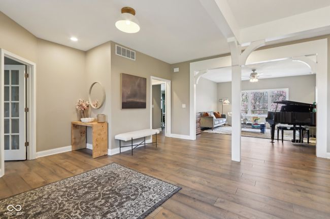 foyer featuring visible vents, hardwood / wood-style flooring, baseboards, a ceiling fan, and arched walkways | Image 10