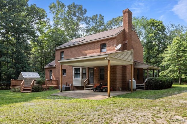 Rear view of house featuring a greenhouse, brick siding, a lawn, and an outbuilding | Image 37