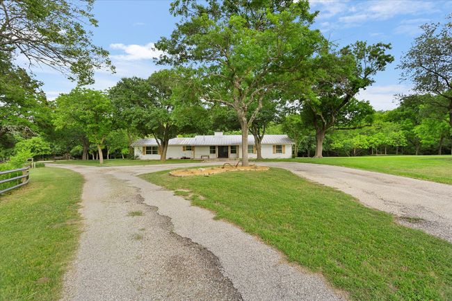 View of front of house with aphalt driveway, a chimney, metal roof, fence, and a front lawn | Image 15