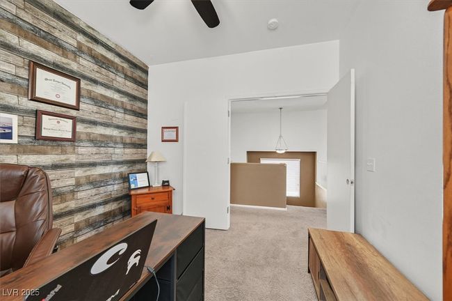 Carpeted office space with wood walls, ceiling fan, and an accent wall | Image 5