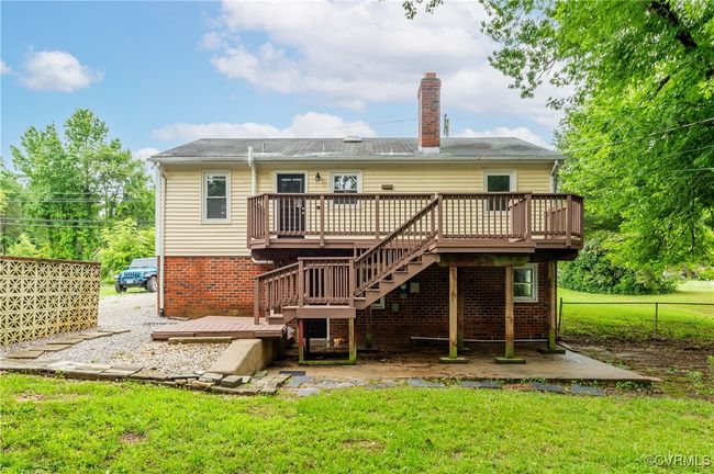 Back of house featuring a wooden deck, a chimney, stairs, and brick siding | Image 29