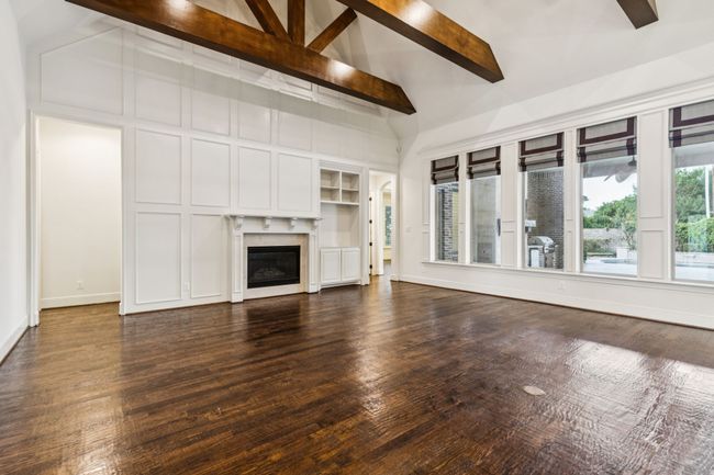 Unfurnished family area featuring a glass covered fireplace, abundance of natural light, dark wood-style flooring, and baseboards | Image 10